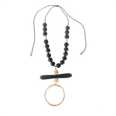 Espectacular collar ajustable de cuentas de madera lacada en negro con un montaje central con detalles en hueso tallado, una cuenta de madera alargada y un aro de zamak con baño de oro mate que hacen que esta pieza sea ideal para combinar con tu look favorito.